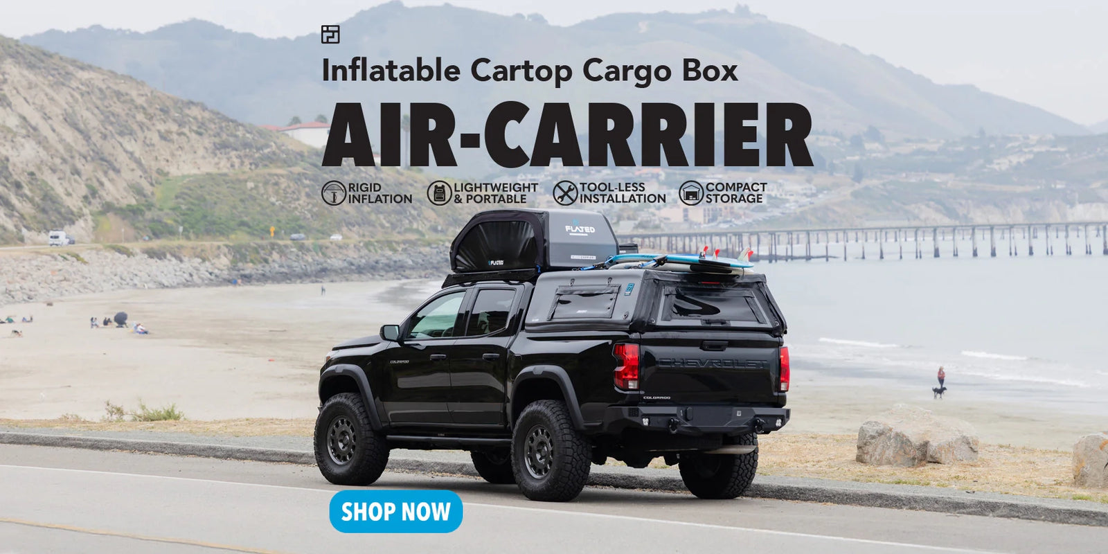 Black truck with inflatable rooftop cargo box on a scenic road.