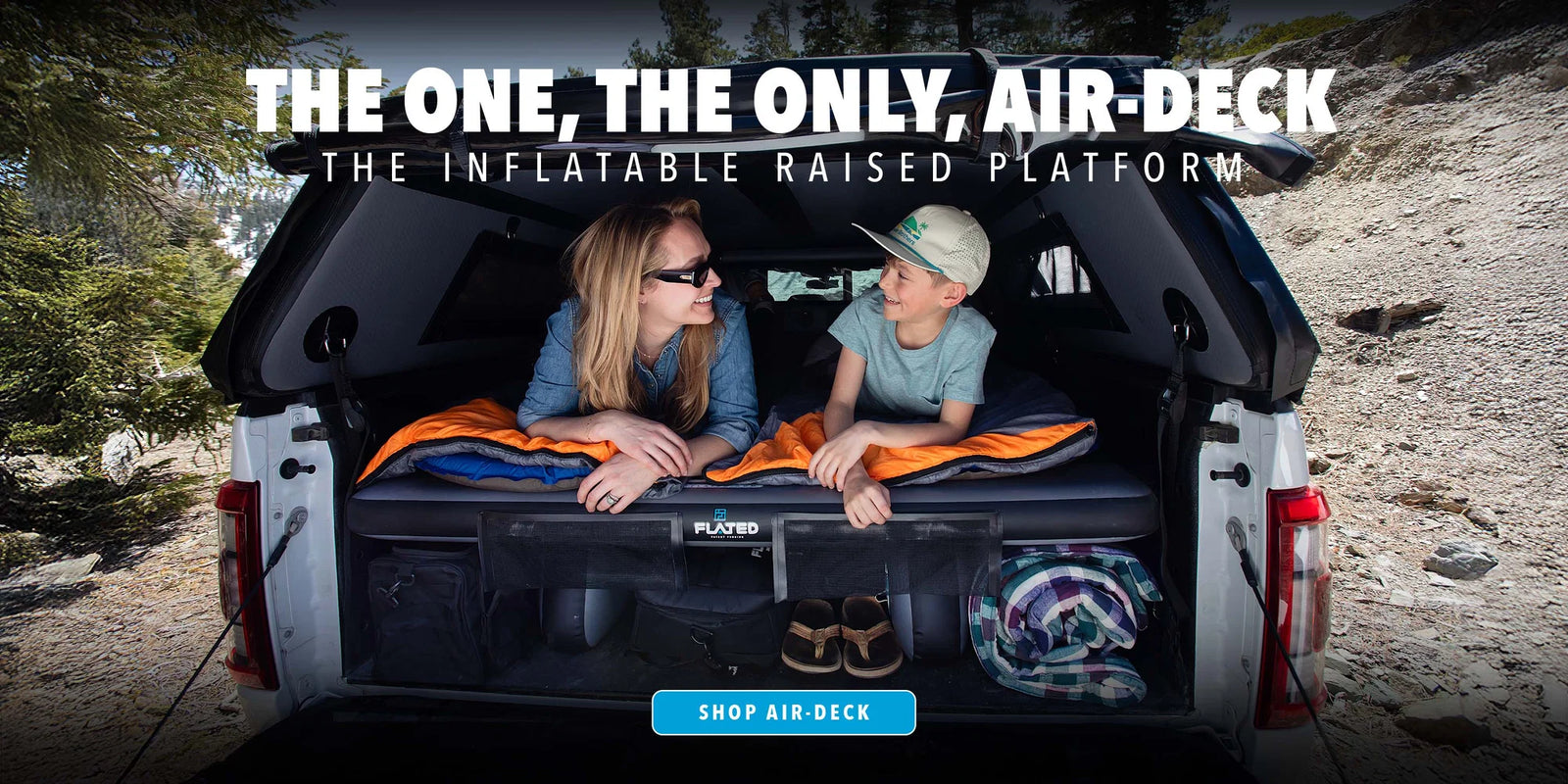 Two people sitting on an inflatable raised platform in a vehicle's trunk with promotional text.